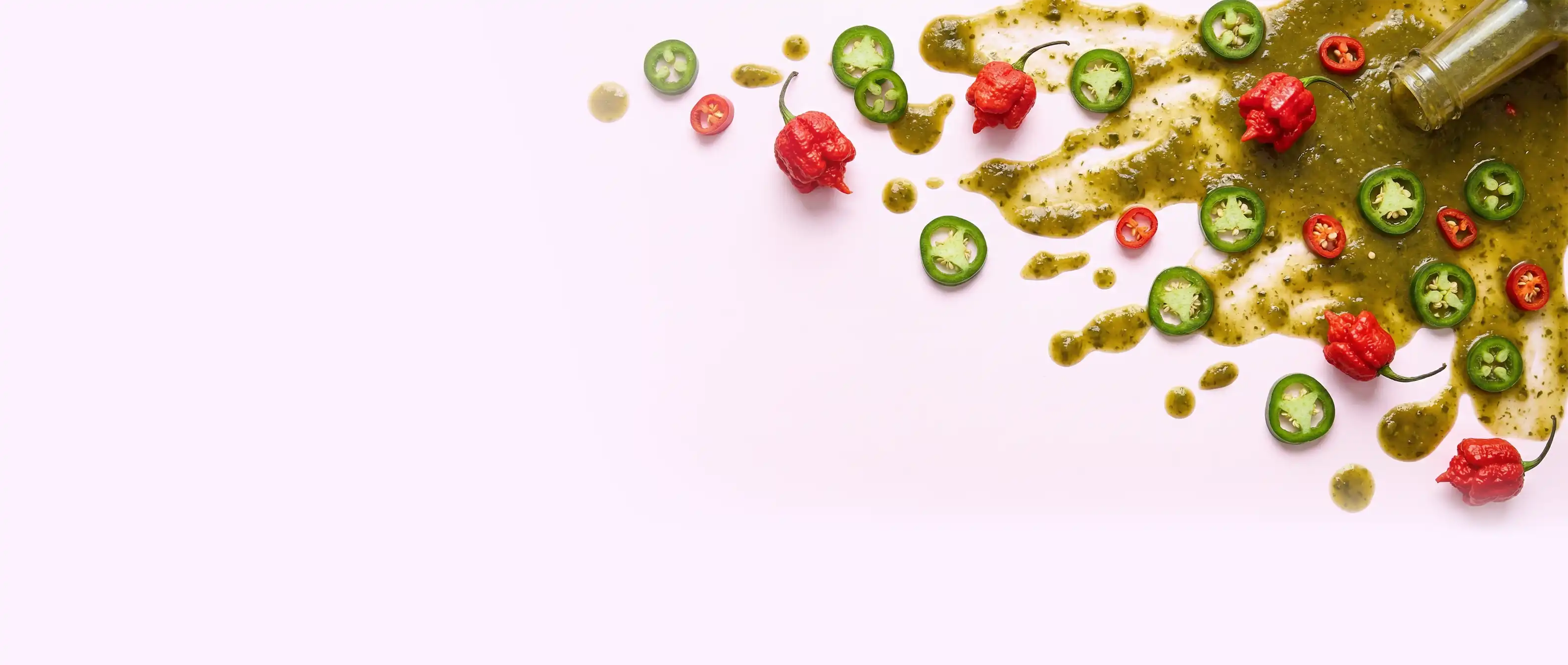 Chilis und Chili Hot Sauce auf rosa Hintergrund