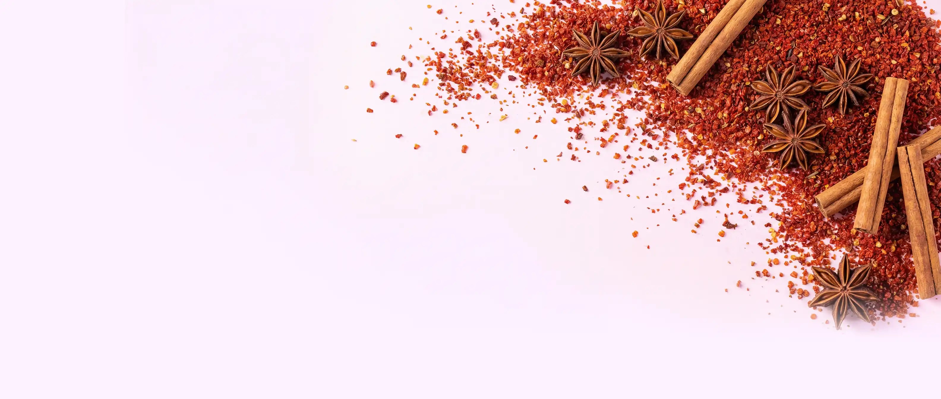 Gewürzpulver Sternanis und Zimtstangen auf rosa Hintergrund
