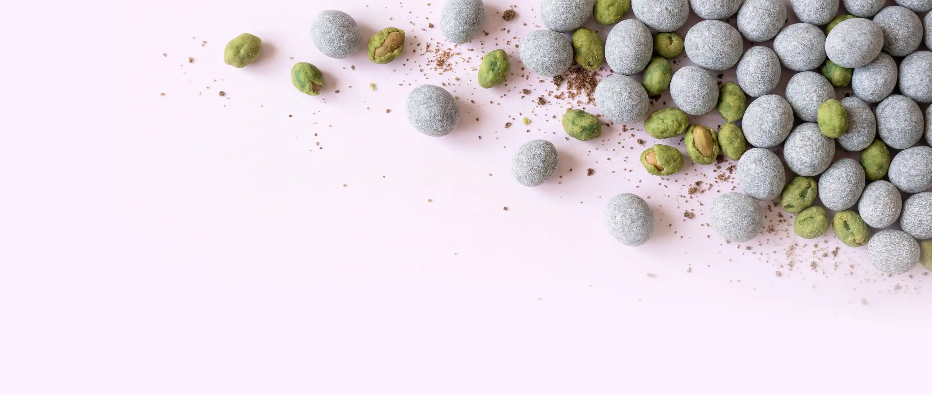 Schokolinsen und Wasabi Nüsse auf rosa Hintergrund